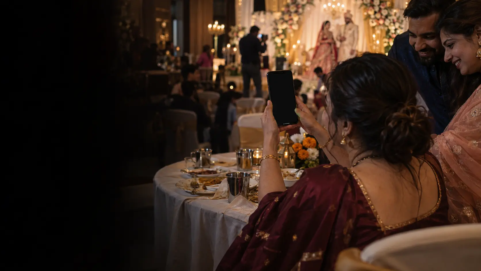 A wedding guest at a reception showing the people at her table the photos she just got on her phone
